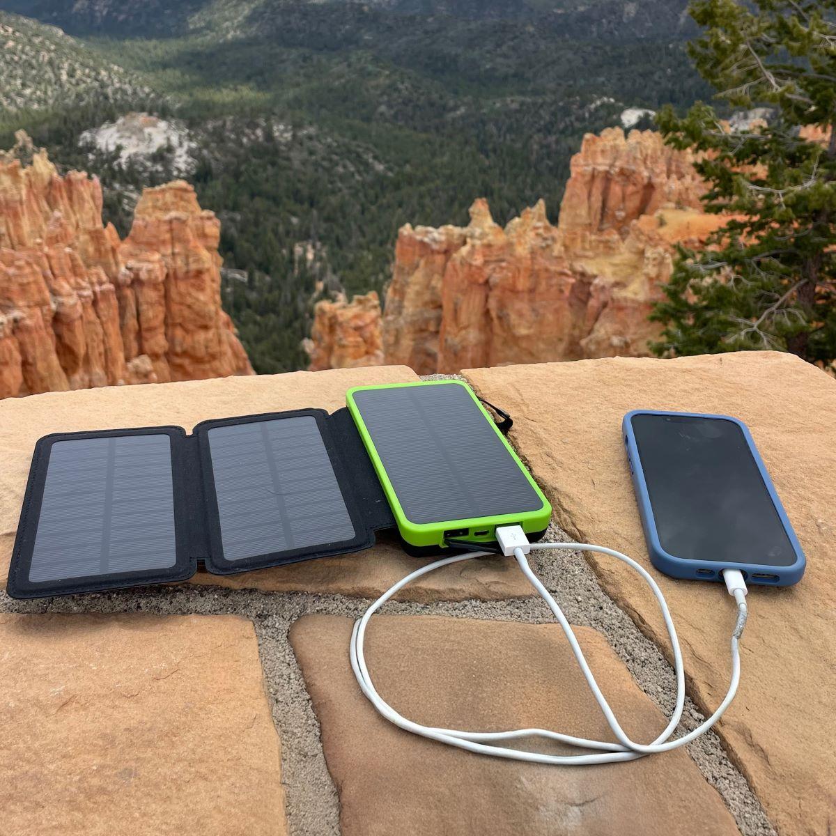 JackPak PB20KS solar power bank charging a smartphone in a canyon, ideal for remote adventures.